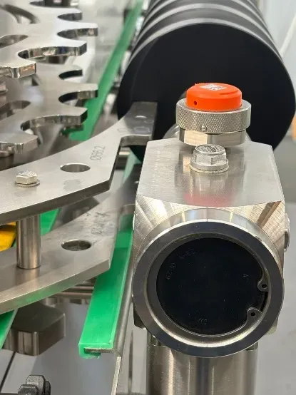 Side view of the wireless triaxial accelerometer installed next to the filling machine conveyor