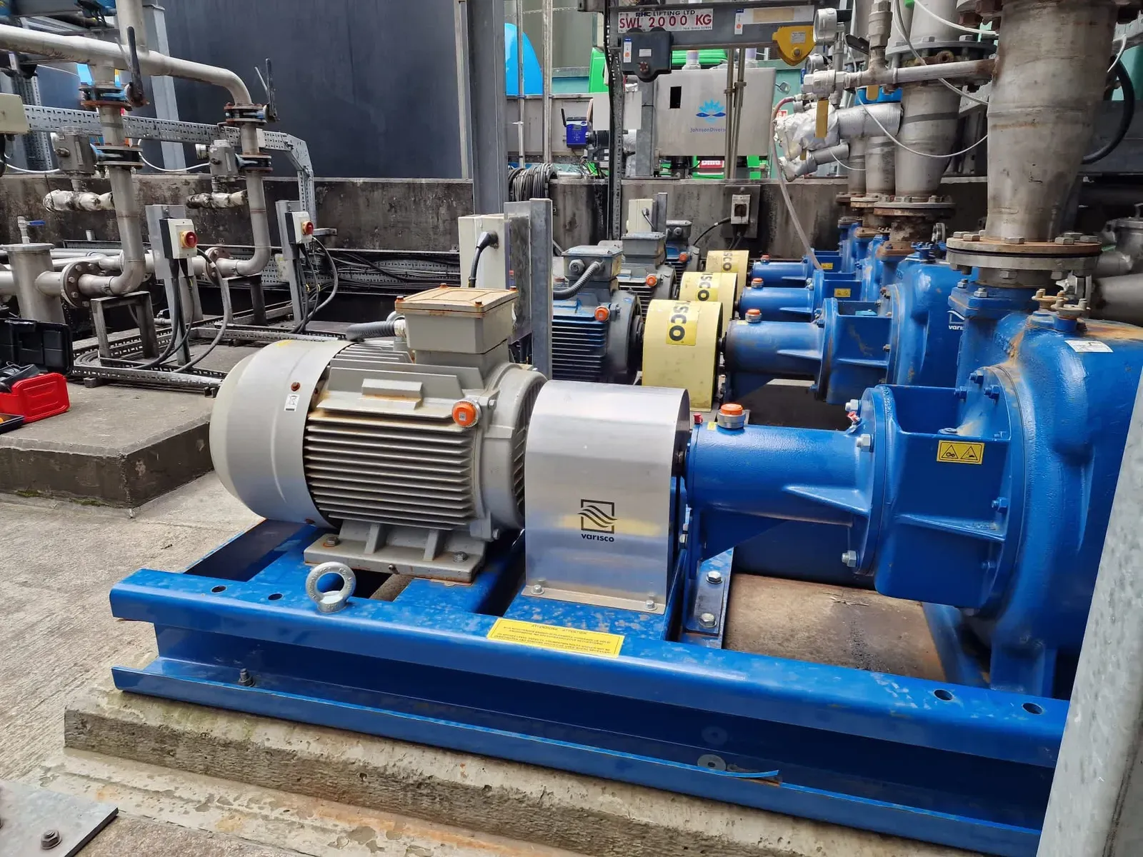 A row of Varisco pumps in a plant, each motor fitted with an orange-capped PHANTOM® wireless vibration sensor